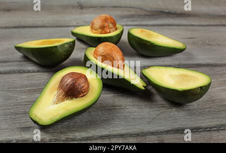 Avocados cut in half, seed visible, on gray wood desk. Stock Photo