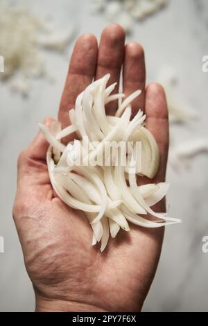 Julienne cuted onions on mans hand. Photo show how does julienne sliced or pole to pole to root to stem or half rings onions look like Stock Photo