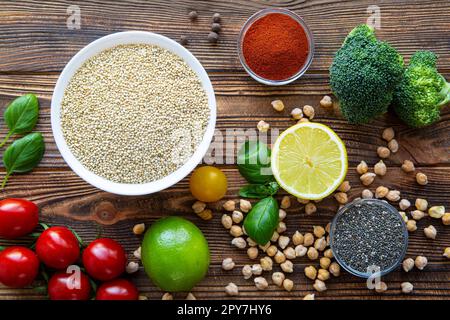 Assortment of quinoa and other superfood seeds and vegetables on wooden background. Vegetarian or vegan concept. Stock Photo