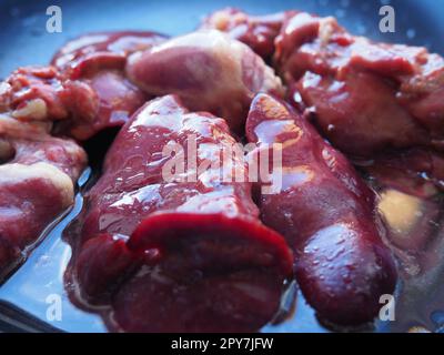 chicken liver, kidney and heart in a non-stick skillet. The offal of the bird is placed in a dark bowl and sprinkled with vegetable oil. Cooking food high in heme iron. Anti-anemic diet Stock Photo