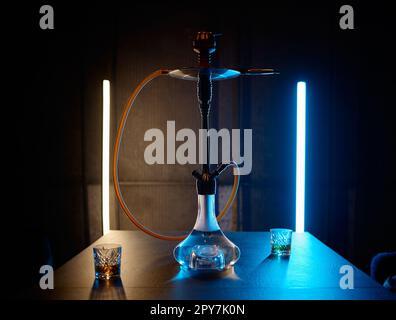 Hookah on table with glasses filled brandy in neon light Stock Photo