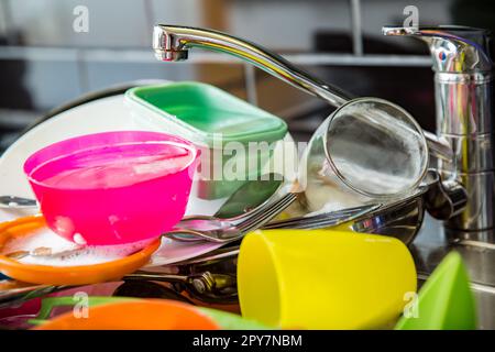 Kitchen sink full of dirty dishes. Dark colored countertop in modern kitchen. Household chores concept Stock Photo