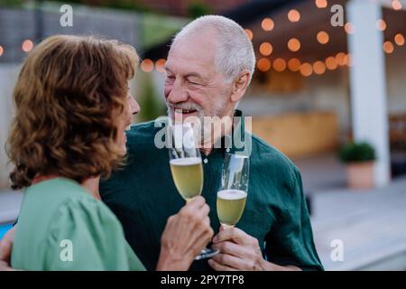 Senior man with his wife celebrating birthday and toasting with wine near backyard pool. Stock Photo