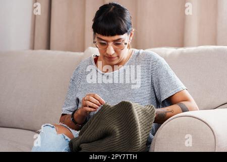 If theres a hole in it, I fix it. a beautiful young woman doing needlework at home. Stock Photo