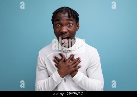 joyful energetic happy dark-skinned young brunette man in a white sweatshirt on the background with copy space Stock Photo