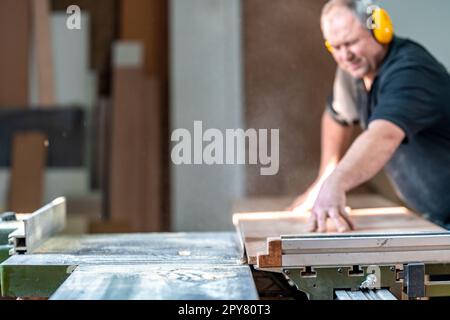 craftsman cuts a laminate board on a saw in a joinery Stock Photo