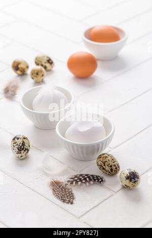 Different eggs with feathers for Easter on white background Stock Photo