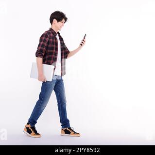 Young Asian businessman walking and watching smart phone Stock Photo