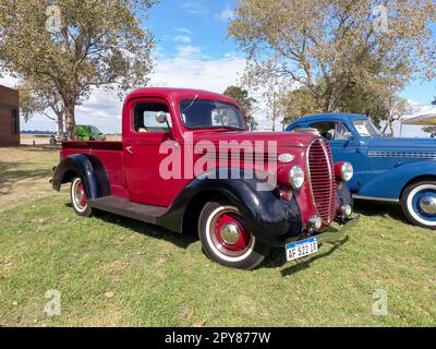 Old red and black utility pickup truck Ford 85 V8 1938 - 1939 on the lawn. Nature grass and trees. CAACMACH 2023 classic car show. Stock Photo