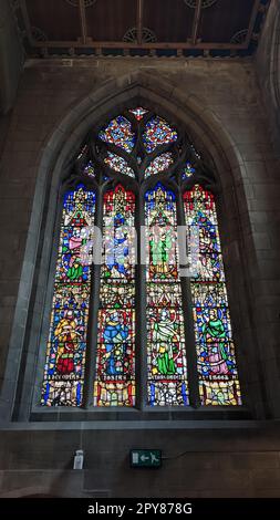 a colorful vintage stained glass window with paintings of saints in a religious church cathedral Stock Photo