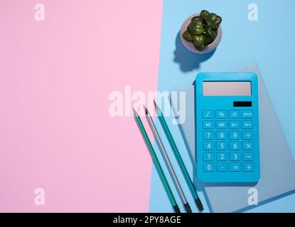 Blue notepad, calculator and wooden pencil on a blue background, top view Stock Photo