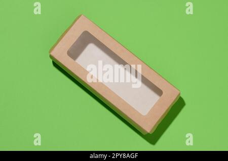 Rectangular cardboard box with a transparent plastic lid on a green background, top view Stock Photo