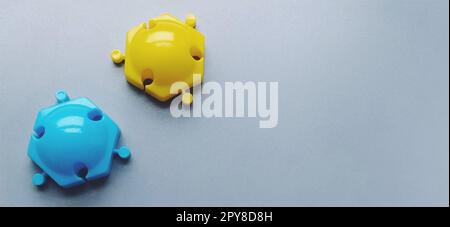 Multi-colored details from the childrens designer on a gray background. Yellow and blue plastic discs for the development of fine motor skills of fingers. Stock Photo