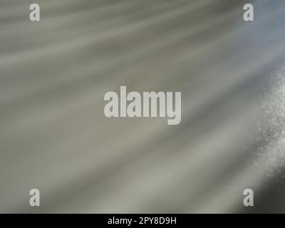 Abstract gray background. Oblique light rays on a grey background with flickering dots. From right top, the lines are directed down and to the left. Glow, flare or shine. Side lighting. Small glow Stock Photo
