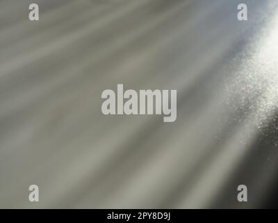 Abstract gray background. Oblique light rays on a grey background with flickering dots. From right top, the lines are directed down and to the left. Glow, flare or shine. Side lighting. Small glow Stock Photo