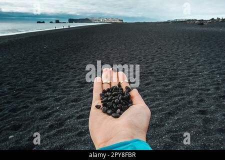 Close up woman showing handful of black pebbles on beach concept photo Stock Photo