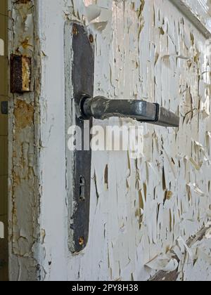 Close-up of door handle of old door with peeling white paint Stock Photo