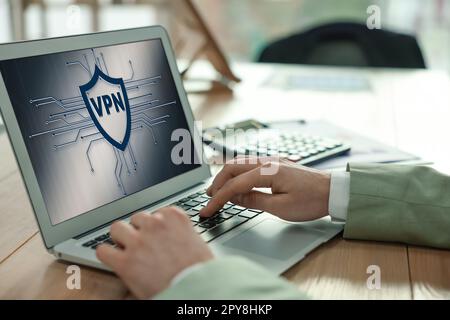 Man using laptop with switched on VPN in office, closeup Stock Photo