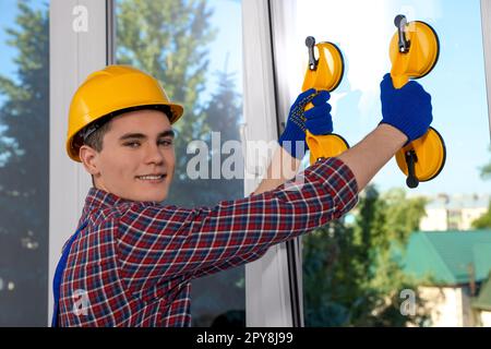 Worker using suction lifters during plastic window installation indoors Stock Photo