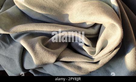 Gray-blue velvet curtains in the living room. The fabric is folded into waves. Short pile. The play of light in the folds of the garment. Beautiful, pleasant to the touch, expensive material Stock Photo