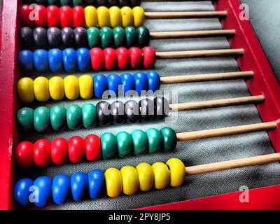 Education concept - abacus with many colorful beads. Red, blue, green, black, yellow details on the abacus. Mathematical exercises. School program Stock Photo