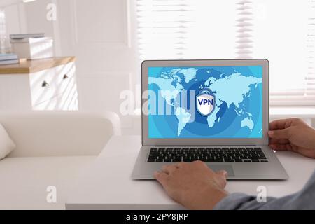 Man using laptop with switched on VPN at white table indoors, closeup Stock Photo