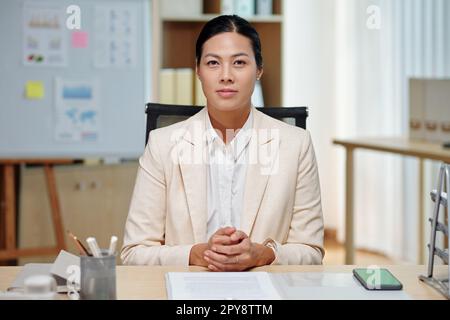 Portrait of serious businesswoman sitting at desk, working with documents Stock Photo