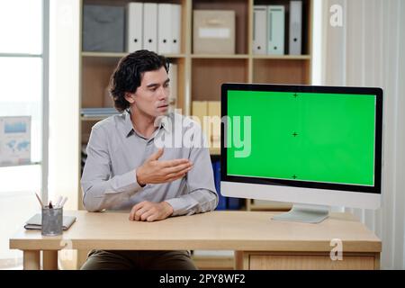 Serious businessman showing presentation on computer screen in meeting with investors Stock Photo