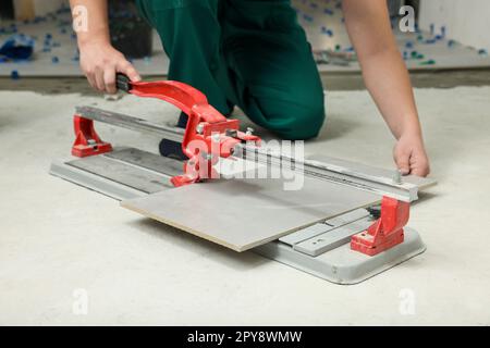 Worker using manual tile cutter on floor, closeup Stock Photo