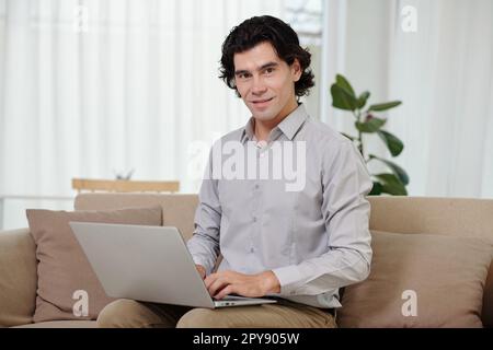 Portrait of smiling businessman working on laptop at home Stock Photo
