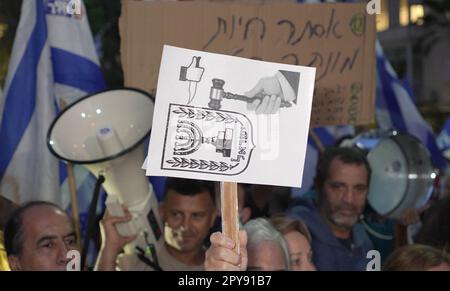 TEL AVIV, ISRAEL - APRIL 30: A right wing protestor holds a sign which shows the Supreme Court stabbing the symbol of the Jewish State during a demonstration held by reform supporters calling for the resumption of the judicial reform near the home of former High Court Justice president Aharon Barak who has been a vociferous critic of the Netanyahu government's judicial overhaul plan on April 30, 2023 in Tel Aviv, Israel. Stock Photo