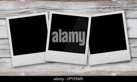 Three empty instant photo frames on wooden table Stock Photo