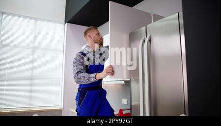 Male Carpenter Assembling White Cabinet On Wall Stock Photo
