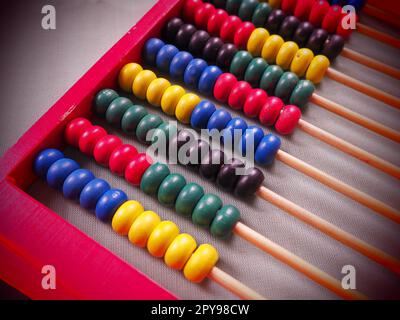 Education concept - abacus with many colorful beads. Red, blue, green, black, yellow details on the abacus. Mathematical exercises. School program Stock Photo