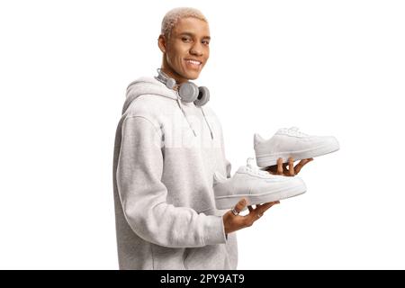 African american young man holding a pair of white sneakers isolated on white background Stock Photo