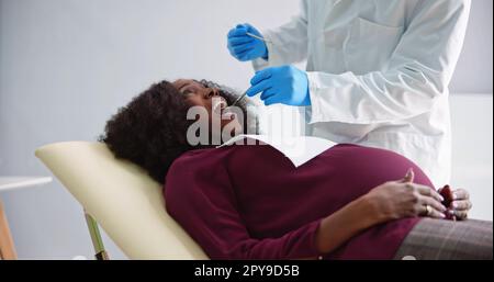 Dentist Treating Teeth Of Young Pregnant Woman Patient Lying Stock Photo