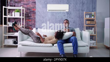 Happy Family Couple Using Air Conditioner Stock Photo
