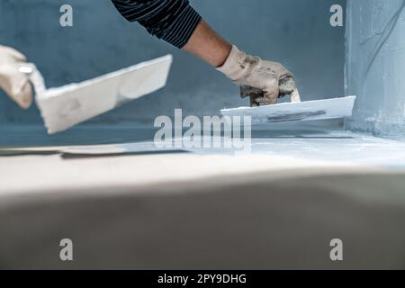 work with trowel on floor and wall in new room in building Stock Photo