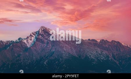Pink purple afternoon clouds sky over mount Krivan peak - Slovak symbol - forest trees silhouettes in foreground, evening scene Stock Photo