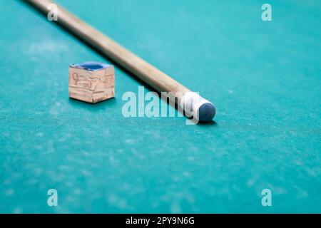 A cue stick and a chalk on a pool table Stock Photo