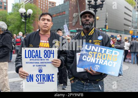 Two men holding signs standing in the middle of a crowd of people at the May Day International Workers Day event in Union Square Stock Photo