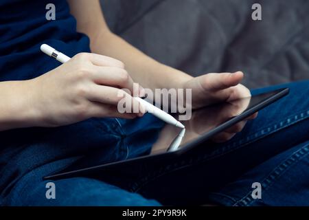 Digital tablet computer in male hands, side view closeup. Young business man work on multitasking gadget with stylus. Stock Photo