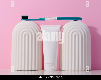 White plastic toothpaste tube and toothbrush on a pink background. Stock Photo