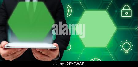 Businessman in black suit standing and holding tablet in two hands. Glow going from device display. Futuristic style image with colored bright glowing. Digital design. Stock Photo