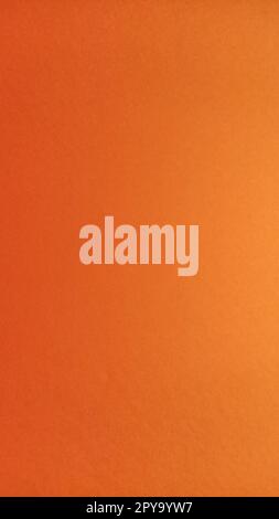A sheet of thick paper of bright orange color. Close-up. Background intense shade. Natural lateral lighting. Fine cardboard or paper texture. Light gradient in degree of illumination. Copy space. Stock Photo