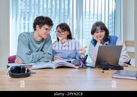 College students with teacher sitting at desk in classroom studying languages, sciences Stock Photo