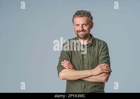 Cheerful and confident man in casual wear stands on white background with hands in pockets, smiling and radiating positive energy. Can be used to represent happiness, positivity, confidence, and friendliness. High quality photo Stock Photo