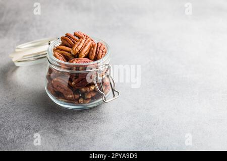 Peeled pecan nuts in jar on kitchen table. Stock Photo