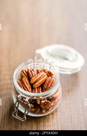 Peeled pecan nuts in jar on kitchen table. Stock Photo