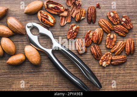 Peeled pecan nuts and nutcracker on wooden table. Top view. Stock Photo